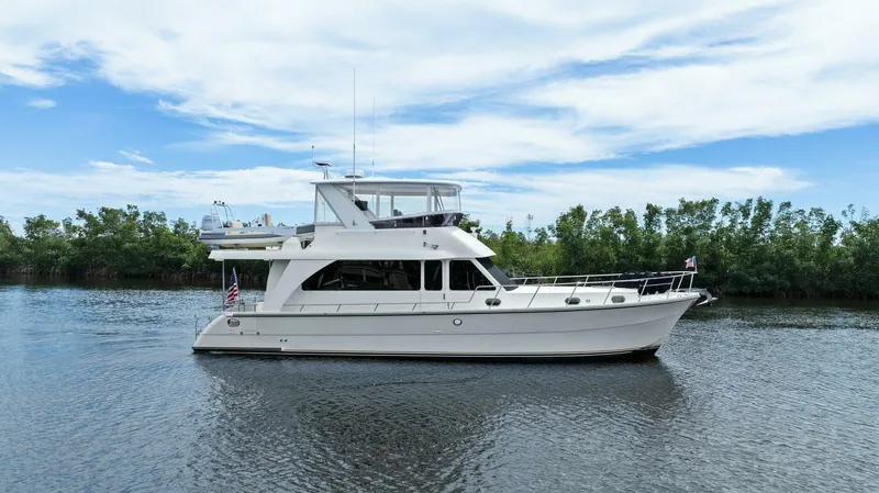 Slide: The Image of A white yacht cruising on a calm river with a clear blue sky. - 0