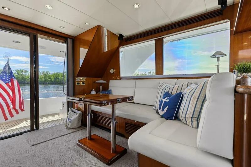 Slide: The Image of Luxurious yacht interior with white seating, nautical pillows, and American flag outside. - 1