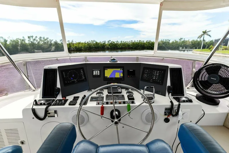 Slide: The Image of Boat cockpit with steering wheel, navigation screens, and controls, overlooking a scenic waterway. - 2