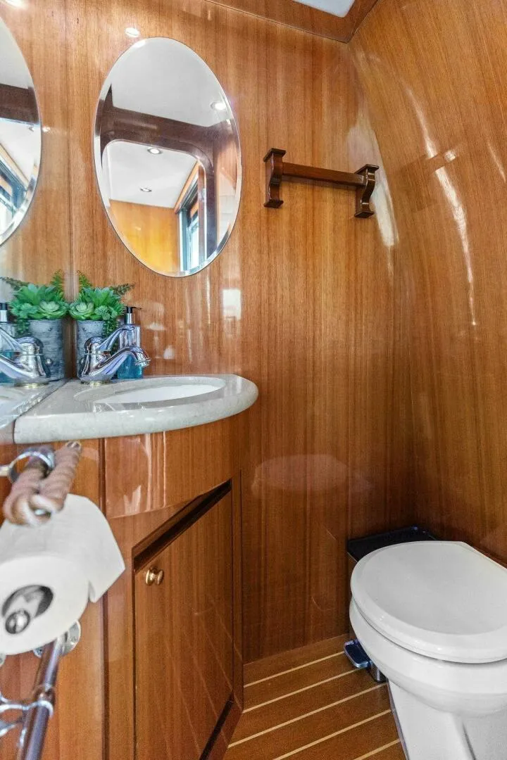 Slide: The Image of Wood-paneled bathroom with oval mirrors, sink, and toilet; modern and compact design. - 36