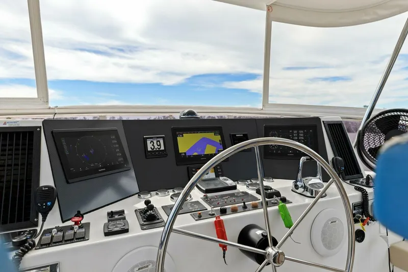 Slide: The Image of Boat cockpit with steering wheel, navigation screens, and controls under a clear sky. - 6