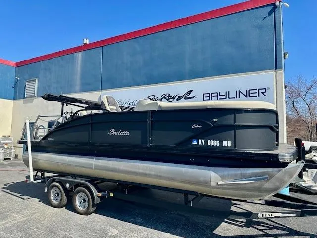 Slide: The Image of 2023 Barletta C20UC pontoon boat on trailer, parked outside dealership. - 1