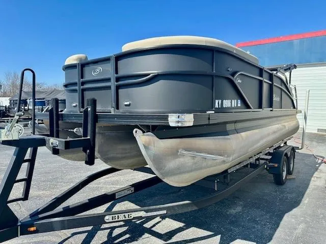 Slide: The Image of 2023 Barletta C20UC pontoon boat on trailer, parked outdoors. - 2