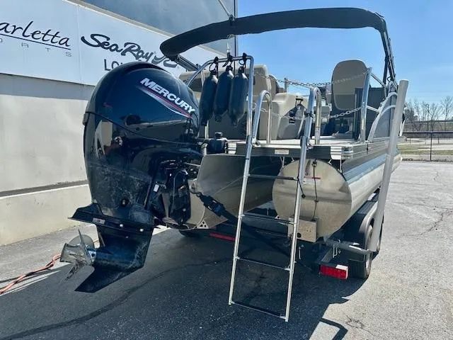 Slide: The Image of 2023 Barletta C20UC pontoon boat with Mercury engine, ladder, and trailer in a parking lot. - 3