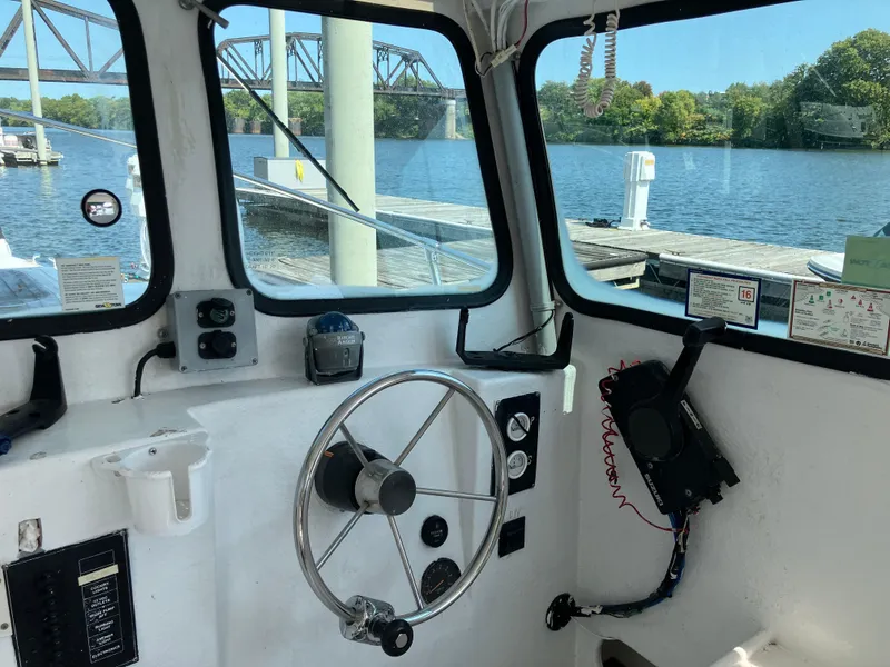 Slide: The Image of Interior view of a 2003 Cape Islander 22 boat cockpit with steering wheel and river backdrop. - 1