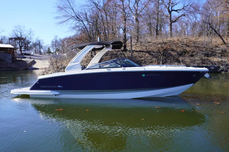 Slide: The Image of 2022 Chaparral 287 SSX boat on a calm lake with a wooded shoreline. - 0