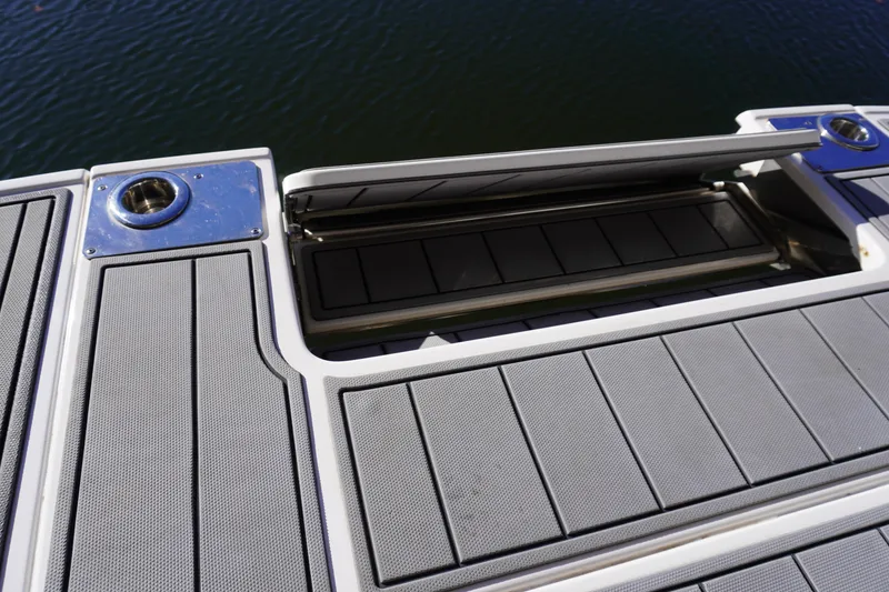 Slide: The Image of 2022 Chaparral 287 SSX boat deck with storage compartment, featuring sleek design and water backdrop. - 3
