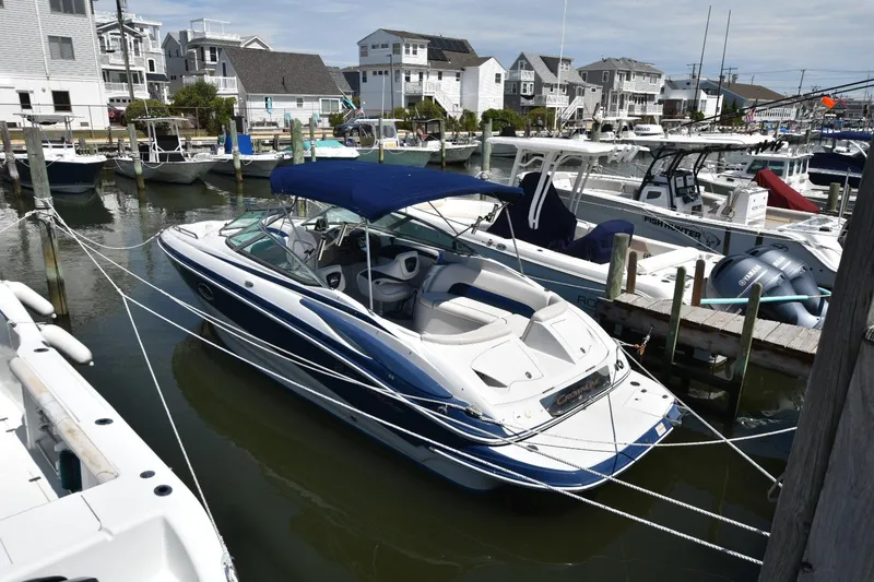 Slide: The Image of 2011 Crownline 265 SS boat docked in a marina, featuring a blue canopy. - 2
