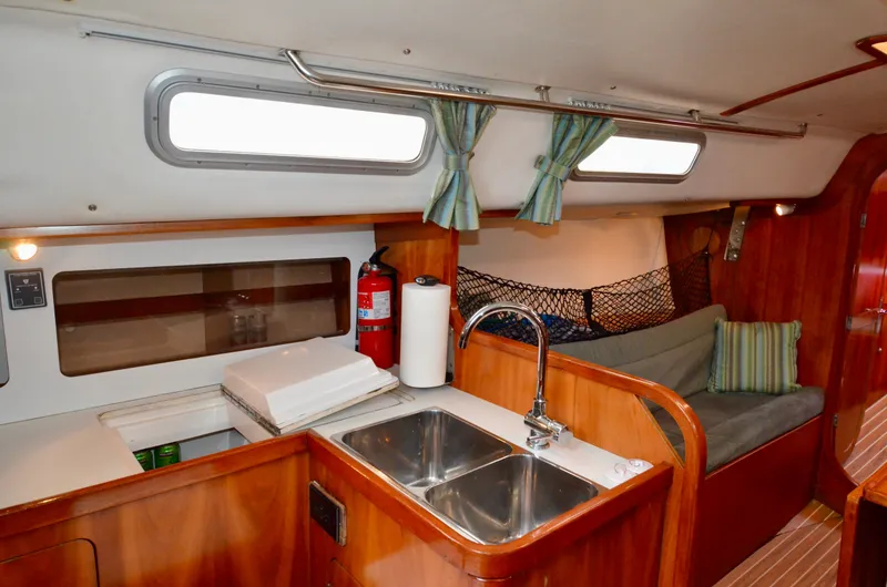 Slide: The Image of 1998 J Boats J/120 interior with kitchen sink, seating area, and wooden cabinetry. - 27