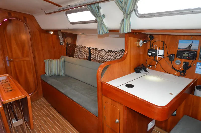 Slide: The Image of 1998 J Boats J/120 interior with wooden finish, sofa, navigation station, and striped cushions. - 29