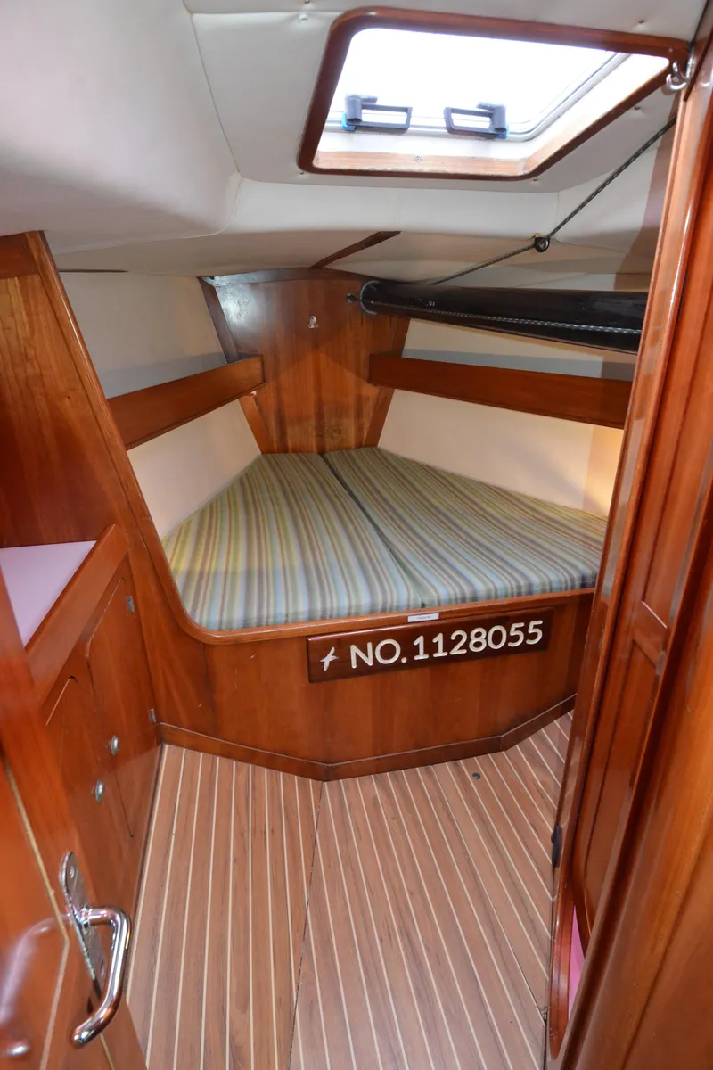 Slide: The Image of 1998 J Boats J/120 cabin interior with wood finish and striped bedding. - 35