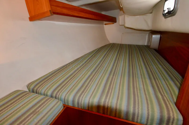Slide: The Image of 1998 J Boats J/120 interior cabin with striped bedding and wooden shelves. - 45