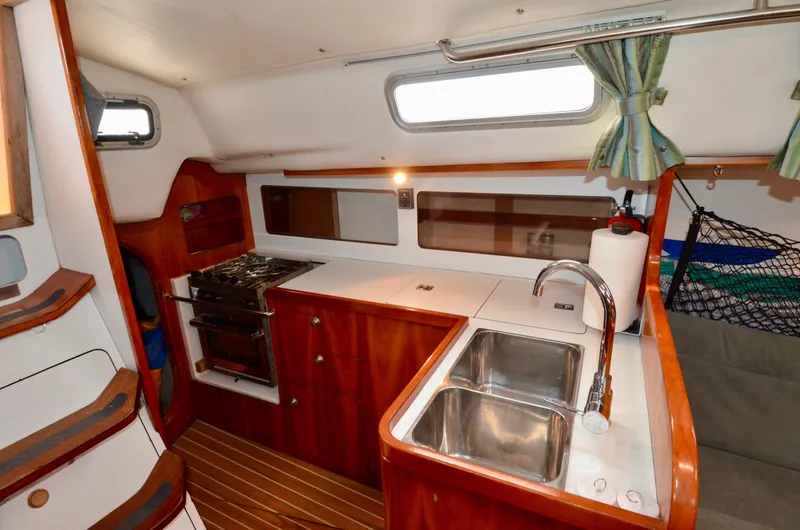 Slide: The Image of Interior of 1998 J Boats J/120 sailboat with kitchen, sink, stove, and wooden cabinetry. - 46