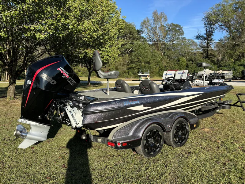 Slide: The Image of 2016 Triton 21 TrX Patriot bass boat with powerful engine, parked on grass. - 13