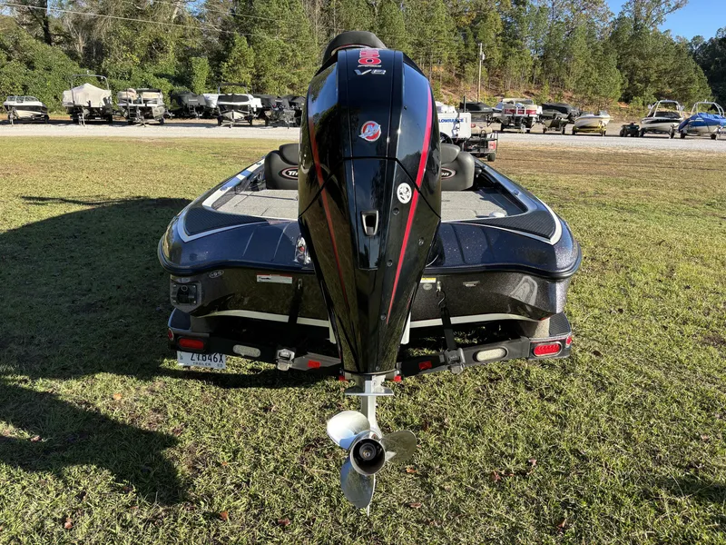 Slide: The Image of 2016 Triton 21 TrX Patriot boat with powerful outboard motor, parked on grass. - 15