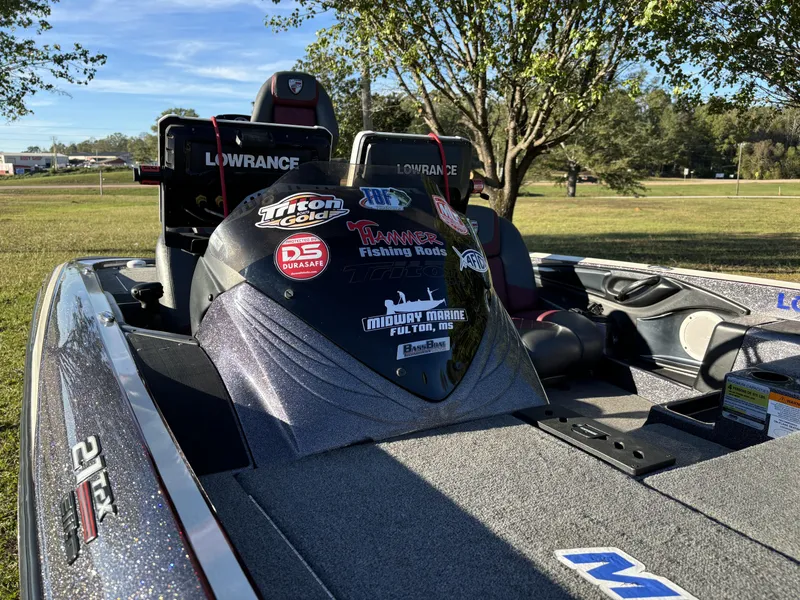 Slide: The Image of 2016 Triton 21 TrX Patriot boat with sponsor decals, parked on grass. - 4