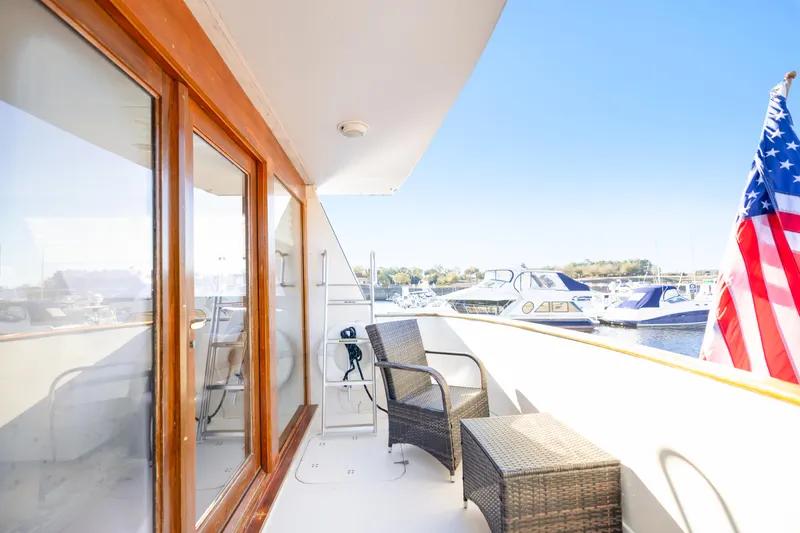 Slide: The Image of 1989 Viking 63 Motor Yacht deck with wicker chairs and American flag. - 16