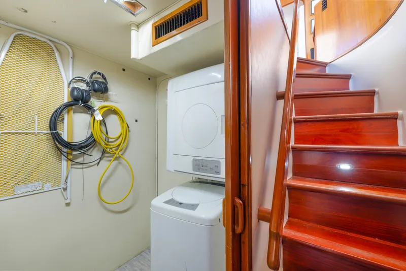 Slide: The Image of Laundry area with washer, dryer, and wooden stairs on a 1989 Viking 63 Motor Yacht. - 25