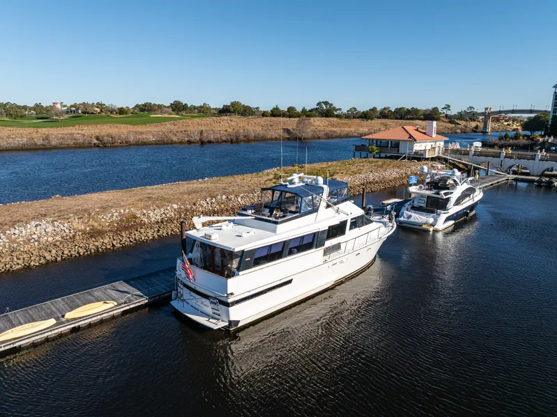 Slide: The Image of 1989 Viking 63 Motor Yacht docked on a serene river under clear blue skies. - 3