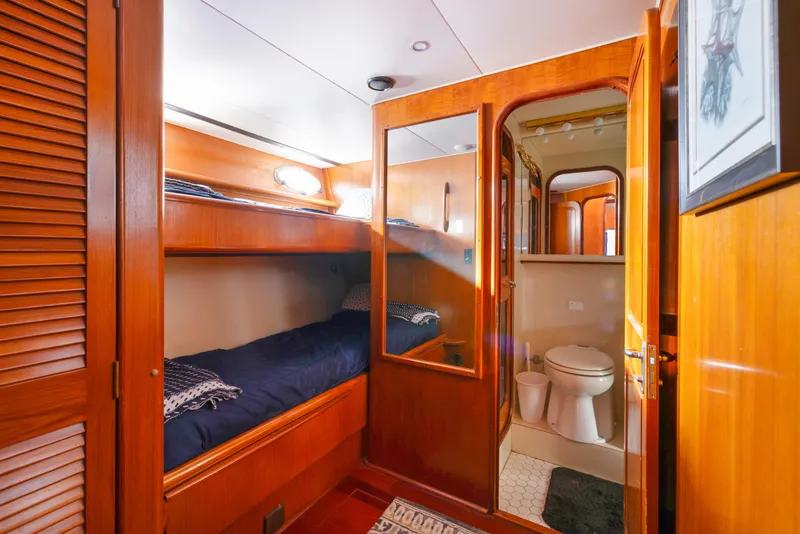 Slide: The Image of 1989 Viking 63 Motor Yacht cabin with wooden interior, bunk beds, and private bathroom. - 32