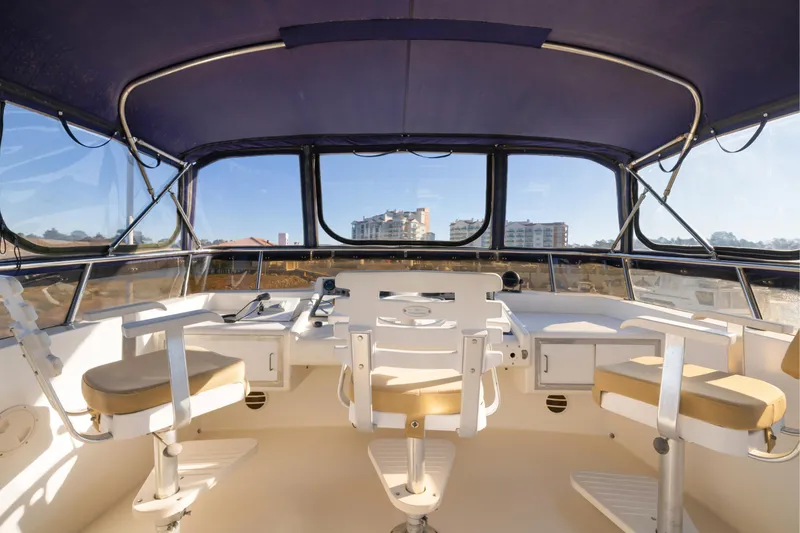 Slide: The Image of Interior view of 1989 Viking 63 Motor Yacht helm with three chairs and panoramic windows. - 38