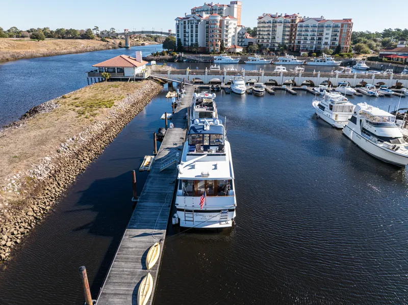Slide: The Image of 1989 Viking 63 Motor Yacht docked at marina with waterfront buildings in background. - 4