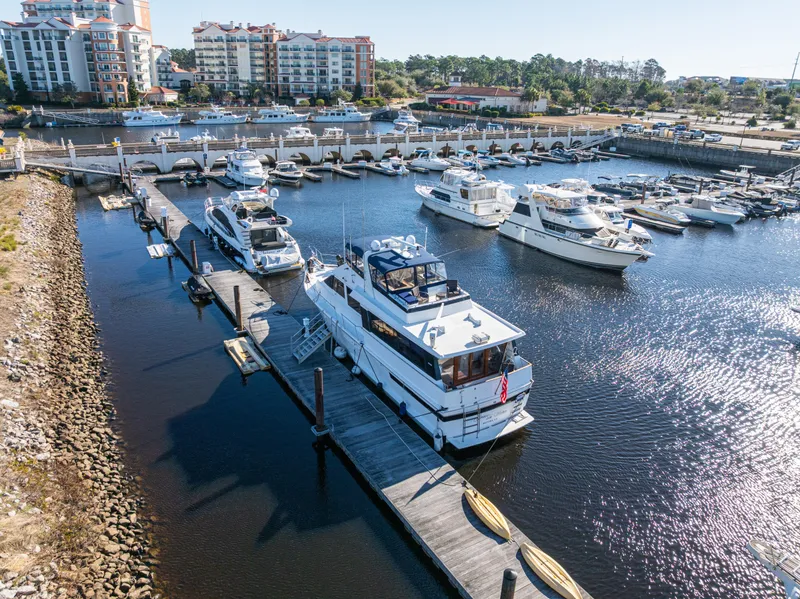Slide: The Image of 1989 Viking 63 Motor Yacht docked in a marina with surrounding boats and waterfront buildings. - 5