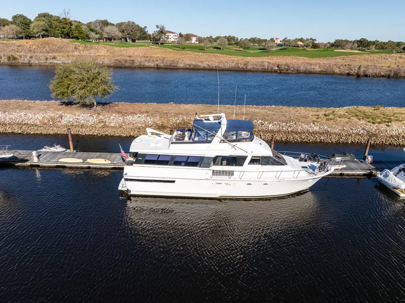 Slide: The Image of 1989 Viking 63 Motor Yacht docked on a serene river with scenic surroundings. - 9