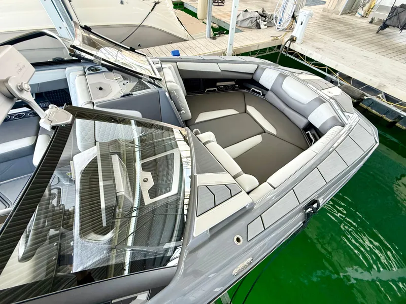 Slide: The Image of 2021 Malibu M240 boat with sleek gray interior, docked on green water. - 10