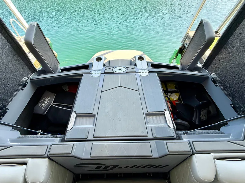 Slide: The Image of 2021 Malibu M240 boat interior with open storage compartments by the water. - 14