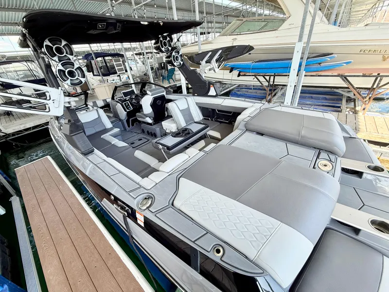 Slide: The Image of 2021 Malibu M240 boat with spacious seating and modern design in a marina setting. - 6