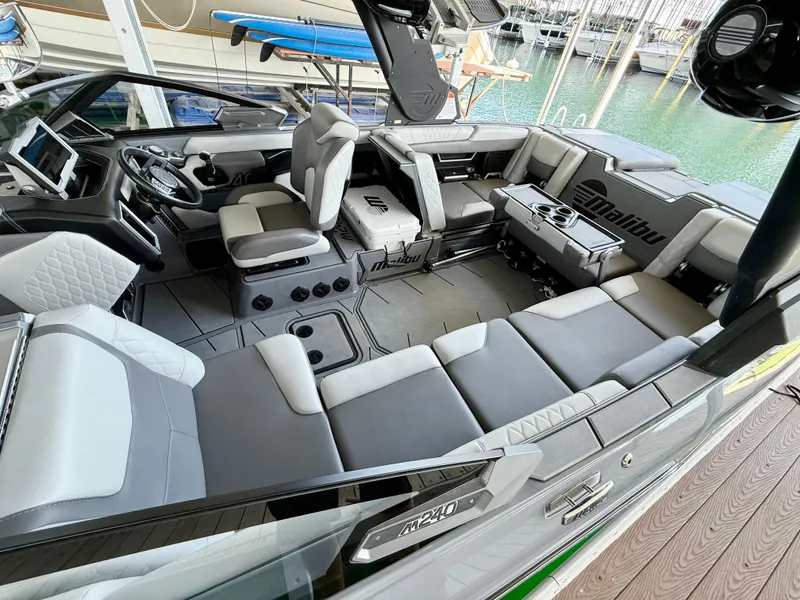 Slide: The Image of 2021 Malibu M240 boat interior with luxurious seating and modern dashboard. - 9