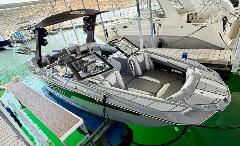 Slide: The Image of 2021 Malibu M240 boat docked in marina, featuring sleek design and spacious seating. - 1