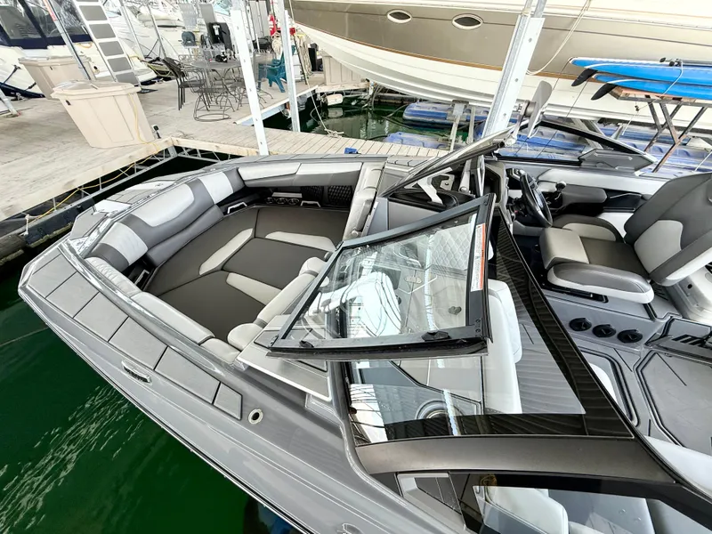 Slide: The Image of 2021 Malibu M240 boat with sleek interior design docked at a marina. - 11