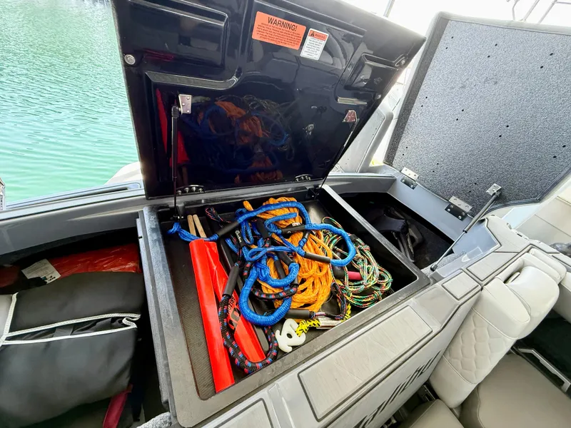 Slide: The Image of Storage compartment in a 2021 Malibu M240 boat filled with ropes and equipment. - 17
