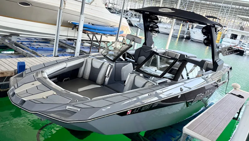 Slide: The Image of 2021 Malibu M240 boat docked in marina, sleek gray design, modern features. - 2