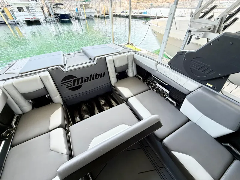Slide: The Image of 2021 Malibu M240 boat interior with gray seating, docked at marina. - 22