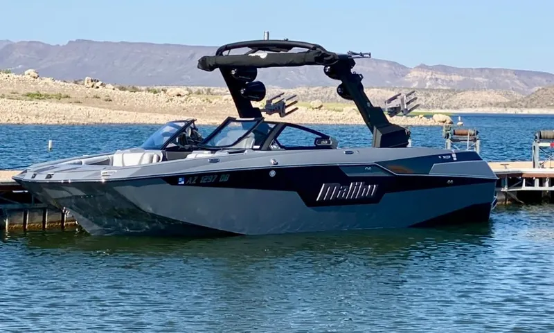 Slide: The Image of 2021 Malibu M240 boat docked on a serene lake with mountainous backdrop. - 35