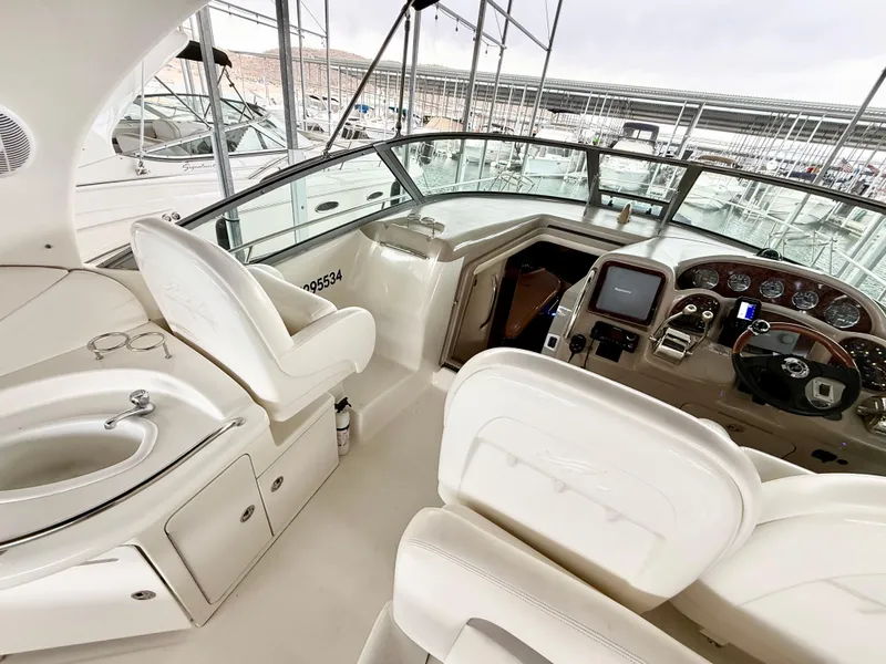 Slide: The Image of 2004 Sea Ray 340 Sundancer cockpit with helm, seating, and control panel in a marina setting. - 10