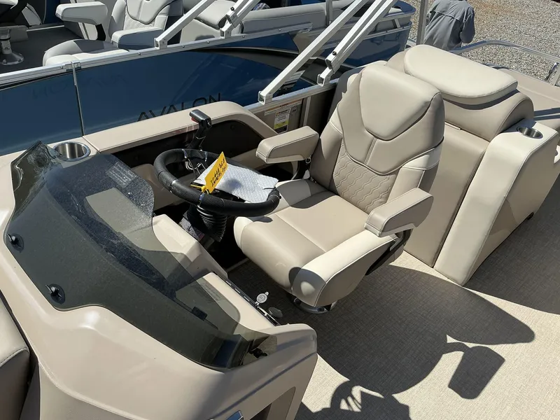Slide: The Image of 2025 Avalon LSZ - 23 FT Rear Lounger boat interior with beige seating and steering console. - 5
