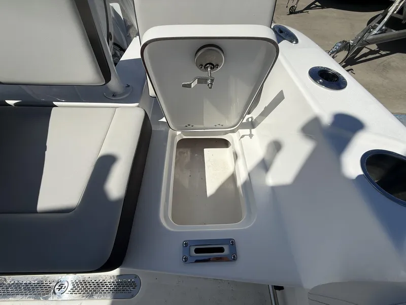 Slide: The Image of Open storage compartment on 2025 Sea Pro 225FLX SANDBAR boat, featuring seating and cup holders. - 16
