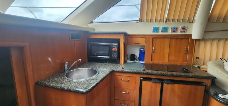 Slide: The Image of 2006 Carver 36 Aft Cabin Motor Yacht kitchen with sink, microwave, and wooden cabinets. - 27
