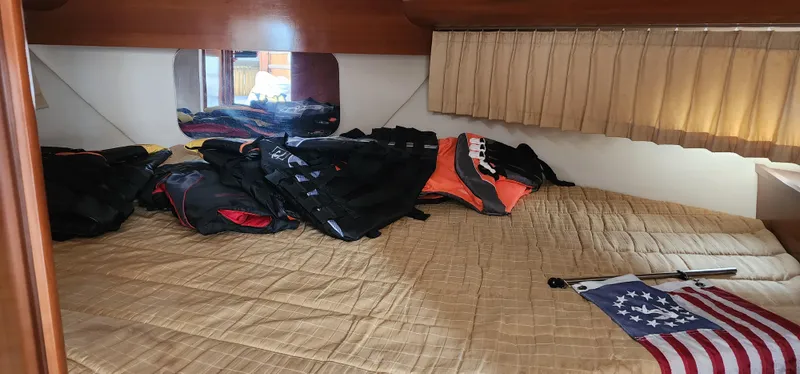 Slide: The Image of 2006 Carver 36 Aft Cabin Motor Yacht interior with bed, clothes, and American flag. - 28