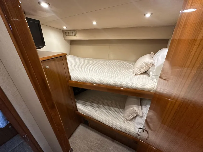 Slide: The Image of 2008 Viking 64 Enclosed Bridge cabin with bunk beds and wooden finishes. - 23