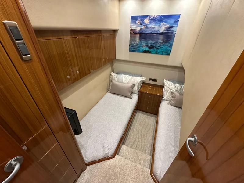 Slide: The Image of Interior of 2008 Viking 64 Enclosed Bridge yacht with twin beds and wooden cabinetry. - 26