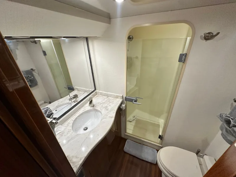 Slide: The Image of Luxurious bathroom in 2008 Viking 64 Enclosed Bridge yacht with marble countertop and glass shower. - 28