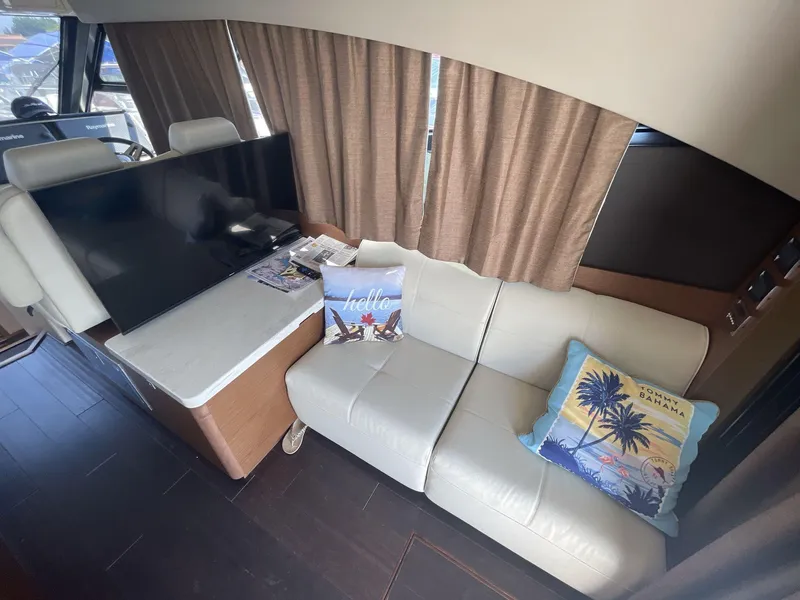 Slide: The Image of Interior of 2016 Sea Ray 470 Sundancer with sofa, TV, and decorative pillows. - 9