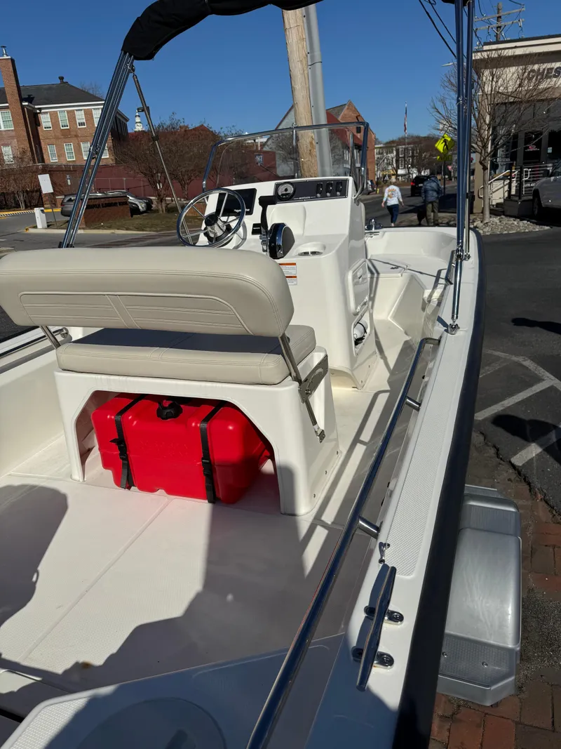 Slide: The Image of 2022 Boston Whaler 150 Montauk boat with seating and red fuel tank, parked outdoors. - 4