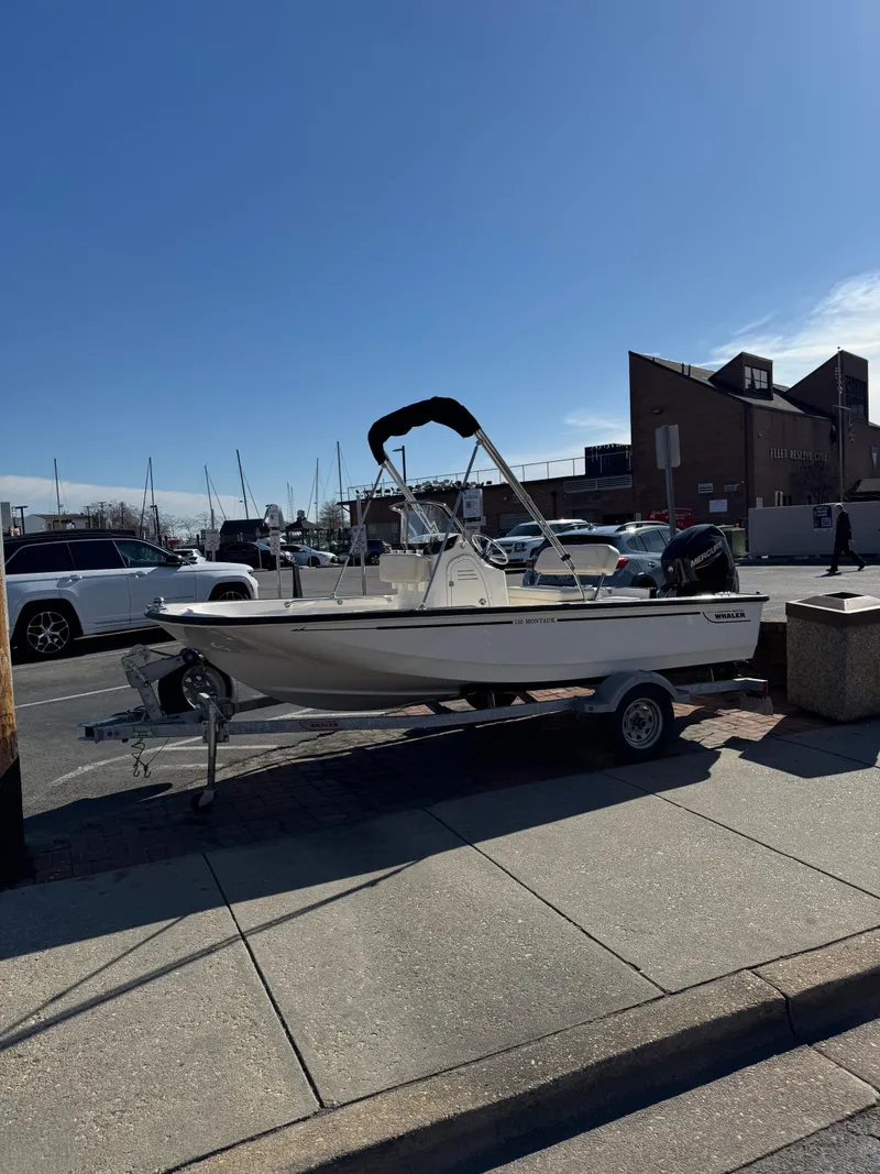 Slide: The Image of 2022 Boston Whaler 150 Montauk boat on trailer in urban setting. - 6