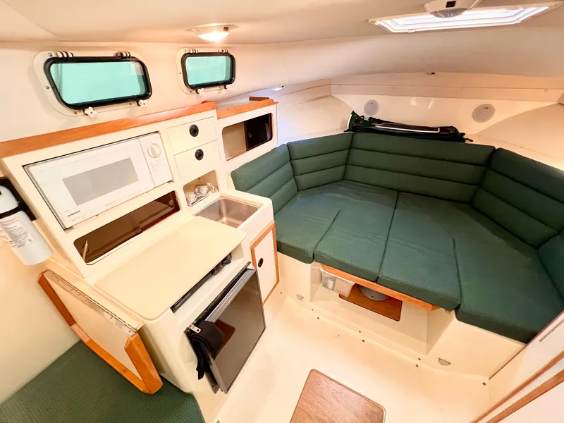 Slide: The Image of Interior of 2000 Albin 28 Tournament Express with kitchenette and green seating area. - 11